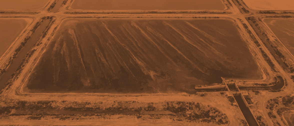 Pan 5 from 300 metres: one concentrating brine pan, the water dense and opaque and streaked in long wind lanes, hard geometric banks on every side.